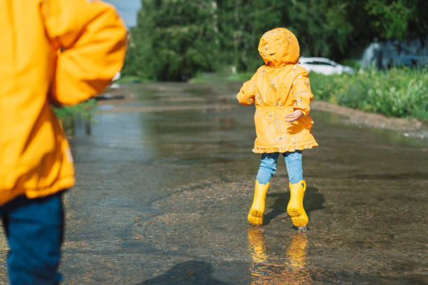 istock Children in yellow rubber boots walk through puddles 1426240009