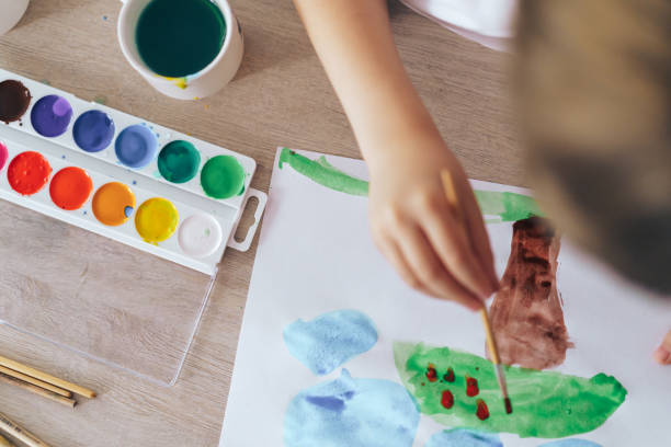 istock Children paint green grass with a tree and blue clouds 1426240062