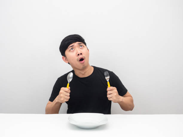 istock Man holding cutlery feeling hungry and looking up at copy space amazed emotion 1426241838