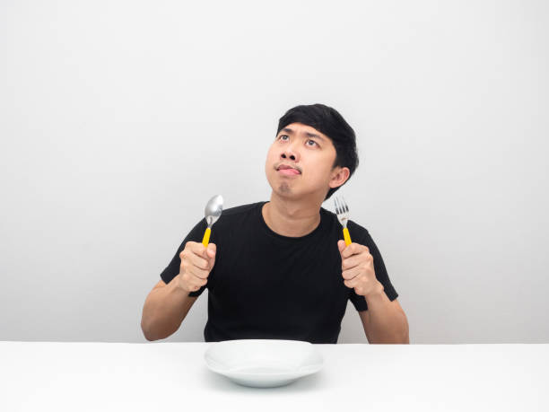 istock Man holding cutlery feeling hungry and looking up at copy space 1426241873