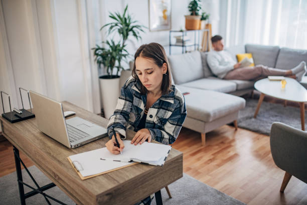 istock Young woman working from home while her boyfriend using smart phone next to her 1426245089