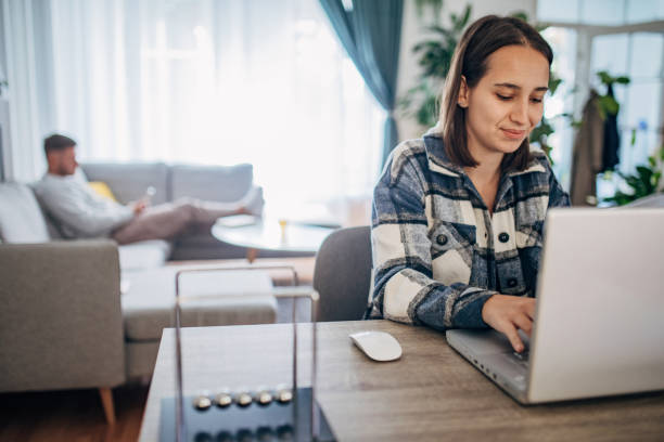 istock Young woman working from home while her boyfriend using smart phone next to her 1426245266