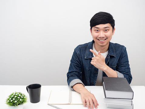 Businessman sit at workplace smile and point finger at copy space