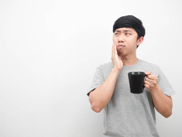 istock Man grey shirt holding coffee cup gesture toothache looking at copy space 1426246013