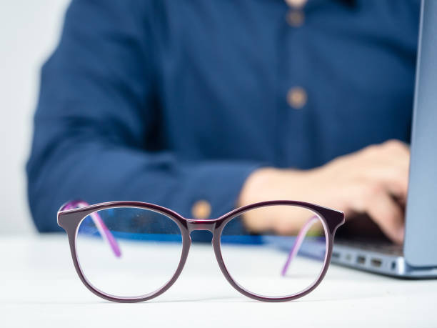 istock Close up glasses on the table with man working with laptop behide 1426246064