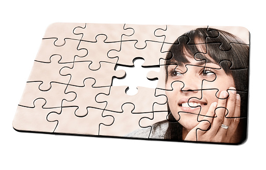 Jigsaw puzzle, with one missing piece, of a young woman looking deep in thought.
