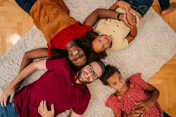 multiracial family lying on the floor - couple loving lying on back carpet imagens e fotografias de stock