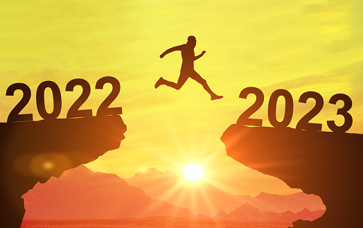 2023. Silhouette man jumping between cliff with number 2022 to 2023. Happy new year and holiday celebration concept. Jump over cliff 2022 and 2023 years. Welcome New Year