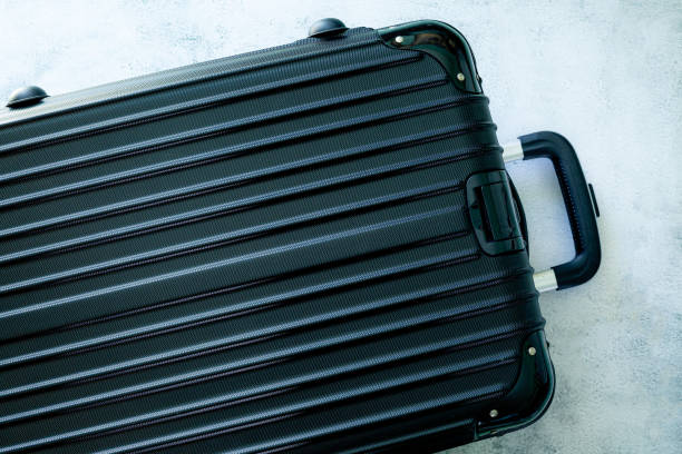 istock black travel bag,Black luggage set on dark background, top view image, flat lay composition. Travel minimalist concept, black and dark classic baggage mockup, small and big. Suitcase accessory set, journey concept. 1426253124