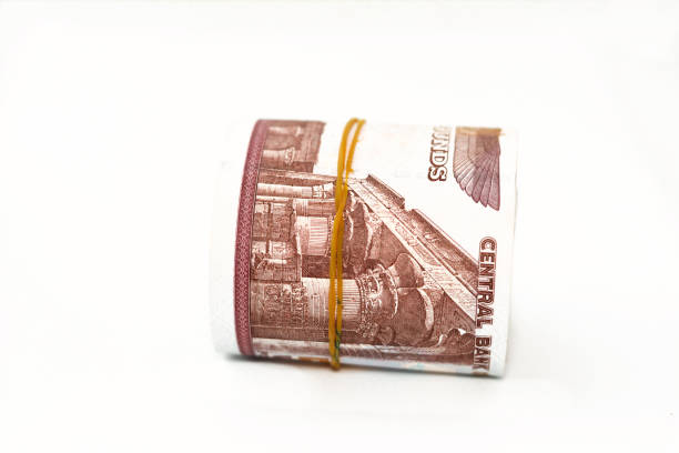 Egypt money roll pounds isolated on white background, 50 LE fifty Egyptian pounds cash money bills rolled up with rubber bands with a image of Abu Hurayba Mosque, temple of Edfu and winged scarab, selective focus peso del rollo de dinero de egipto aislado sobre fondo blanco, 50 le cincuenta libras egipcias billetes de dinero en efectivo enrollados con bandas elásticas con una imagen de la mezquita de abu hurayba, el templo de edfu y el escarabajo alado
