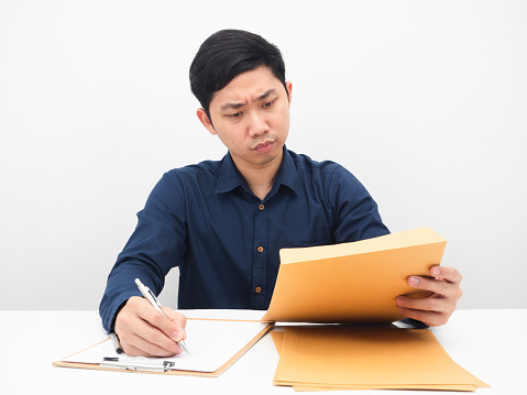 Man working at his workplace looking at document in hand feeling serious and strain white backgound
