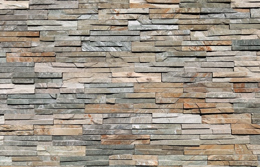 Stone cladding wall made by elongated bricks of natural multicolor rocks. Panels for exterior, background and texture.