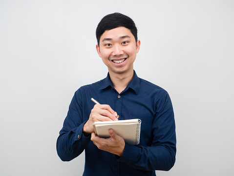 Asian man smiling and gesture writing notebook in hand white background