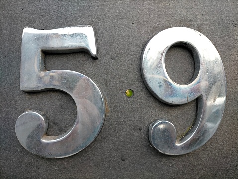Number fifty nine,59 in chrome colored number hooked on a black surface.