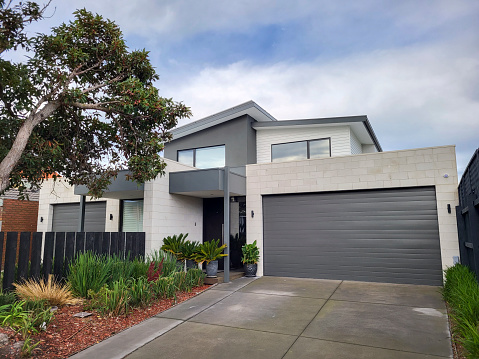 Melbourne, Australia: July 16, 2022: Modern semi-detahced house in the suburb of Chelsea with balcony, large double garage and landscaped garden to the front.