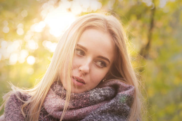 sad girl in scarf in sunlight in autumn park