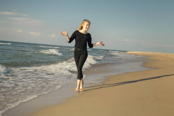 Beautiful bond woman dancing and having fun on beach, enjoying the summer.
