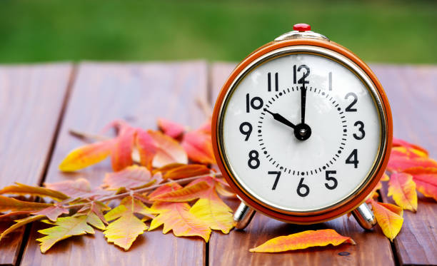 istock Retro alarm clock with autumn fall leaves, daylight savings time background 1426274866