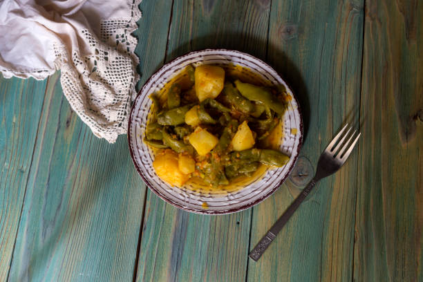 Stewed, green beans and potatoes with vegetables and sauce on a wooden table close-up