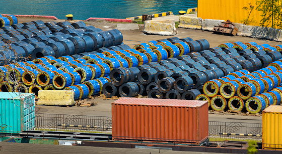 infrastructure of an industrial seaport - sea, rolled metal billets and wire reels for construction and industry, containers loaded onto the railway, the concept of sea cargo transportation