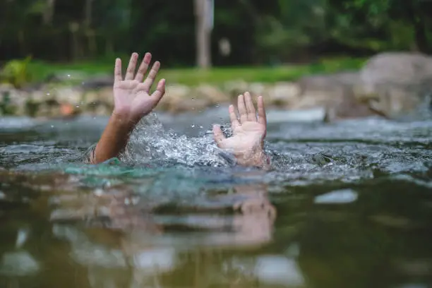 Person drowns in the river reaching for help. Hand drowning children sticking out of the water.