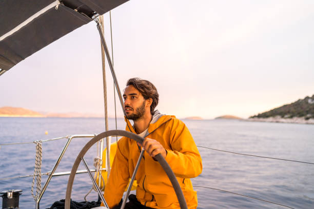 istock Young man steers sailboat on sea 1426287170