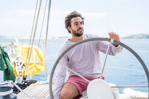 istock Young man steers sailboat on sea 1426287192