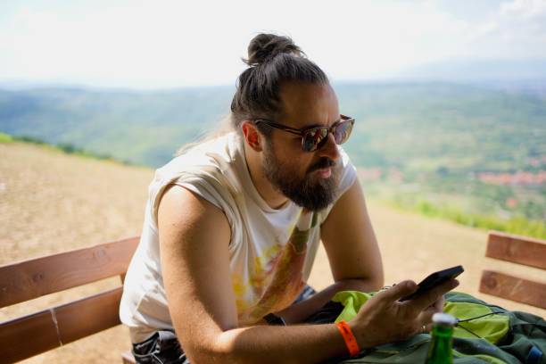istock Cheerful young man relaxing outdoors, looking at the cell phone 1426287263