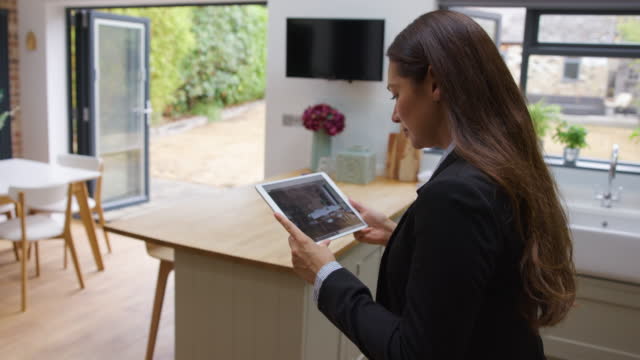 Female real estate agent taking pictures of a residential property using a tablet