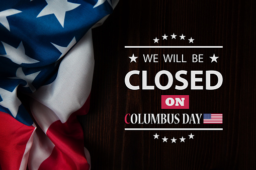 Columbus Day Background Design. American flag on a wooden table with a message. We will be Closed on Columbus Day.