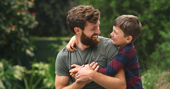 Family, love and bond between father and son at the park for a fun activity, happiness and a hug. Man and boy child feeling playful, happy and joy being active and healthy in nature for time together