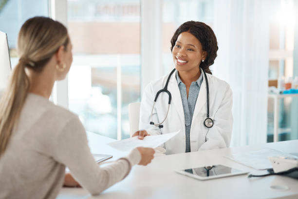 doctor and patient discuss paperwork during medical consultation in a hospital. healthcare professional, gp or physician prepare insurance document and checking personal information at a clinic - healthcare and medicine stethoscope patient report imagens e fotografias de stock