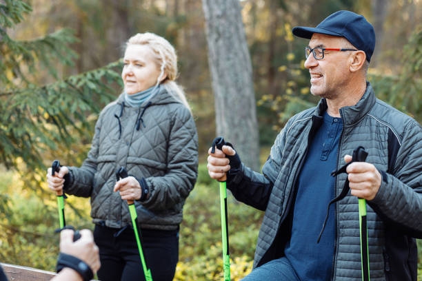 istock Smiling mature, senior people group learning Scandinavian, Nordic walking with professional sticks in forest, chatting 1426302839