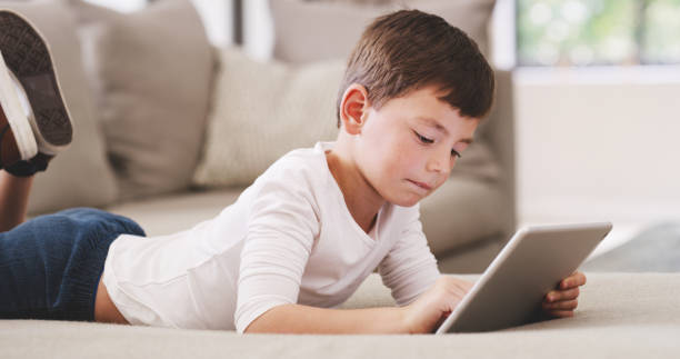 istock Digital tablet boy technology, internet online and watching cartoons while relaxing on sofa at home. Curious young kid child playing on wifi games, fun modern apps and learning educational connection 1426303110