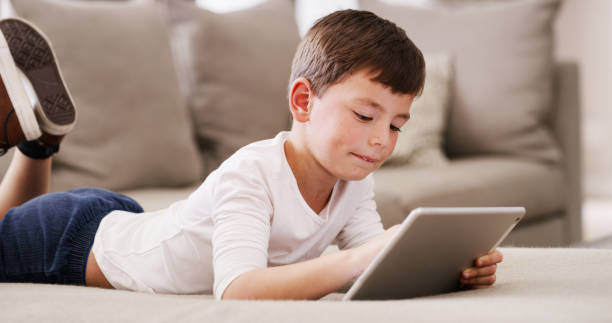 istock Tablet learning, streaming video and kid learning with digital education, relax with online game and in communication on the internet on floor in home. Child with web subscription games on tech 1426303127