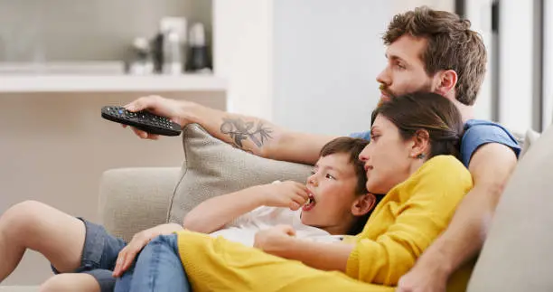 Family popcorn, watching tv and relax in living room for movie, streaming film on subscription service and news on television. Mother, father and kid eating food on the sofa with a film in home