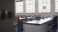 istock Empty classroom with desks, table and chairs to sit for a lesson in modern school, college or campus building closed for covid. Interior education for knowledge study, academic teaching and learning 1426306360