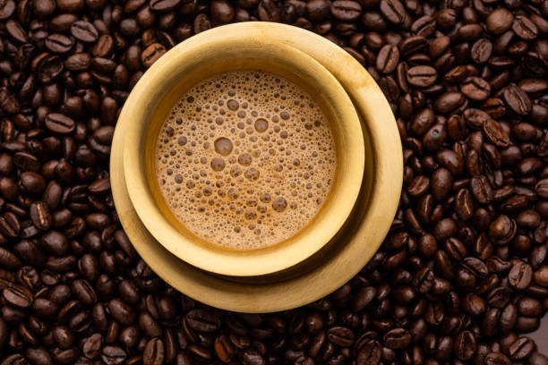 café filtre du sud de l’inde servi dans un gobelet ou une tasse traditionnelle sur des grains crus torréfiés - soap sud photos et images de collection