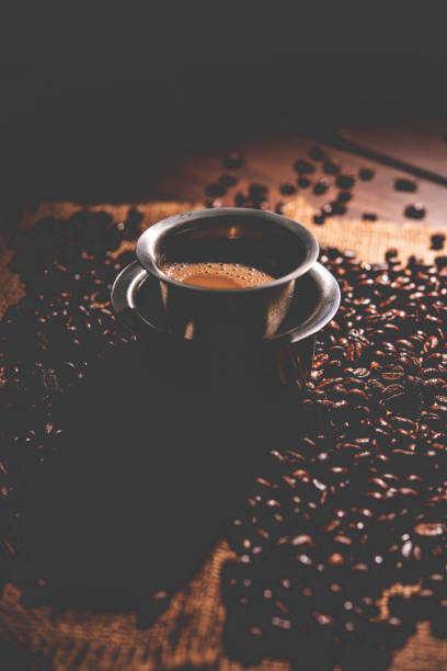 café filtre du sud de l’inde servi dans un gobelet traditionnel ou une tasse sur des grains crus torréfiés - soap sud photos et images de collection