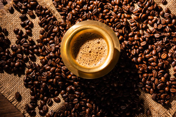 café filtre du sud de l’inde servi dans un gobelet traditionnel ou une tasse sur des grains crus torréfiés - soap sud photos et images de collection