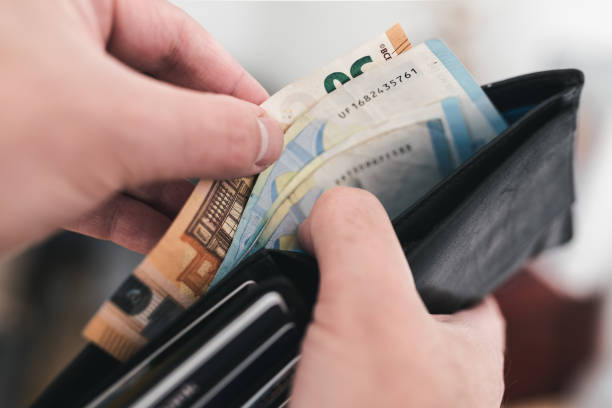 close-up view of hands taking money out of a wallet stock photo