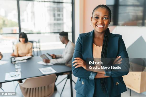 African Leader Manager And Ceo With A Business Woman In The Office With Her Team In The Background Portrait Of A Female Boss Standing Arms Crossed At Work During A Meeting For Planning And Strategy Stock Photo - Download Image Now