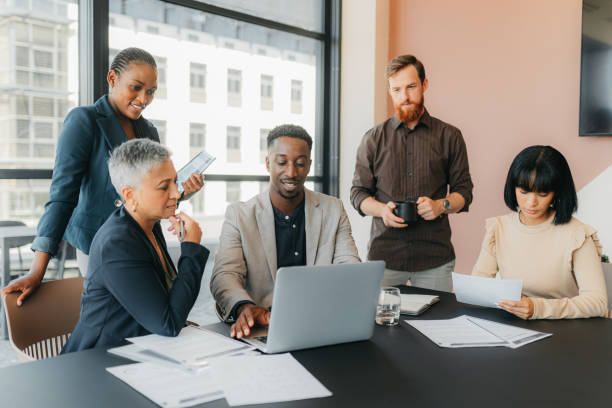 istock Business people planning marketing strategy on laptop, reading documents for project in meeting and discussion in workshop in office. Black man working at diverse global  company with corporate team 1426312120
