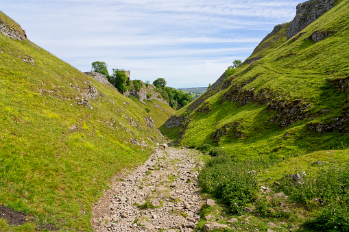 Steep grass covered slopes on either side of a rugged path through Cave Dale.