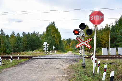 Highway with a railway crossing and a red semaphore signal. Road signs. STOP sign.