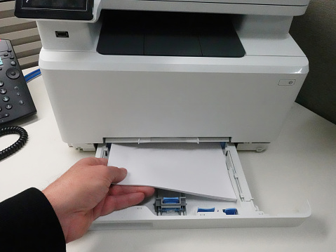 Man loading paper in tray of office printer.