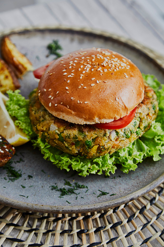 Healthy vegan hamburger on a handmade ceramic plate, made of zucchini, green pea, seasoning, herbs and spices, close up