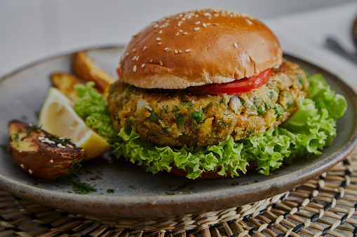 Healthy vegan hamburger on a handmade ceramic plate, made of zucchini, green pea, seasoning, herbs and spices, close up