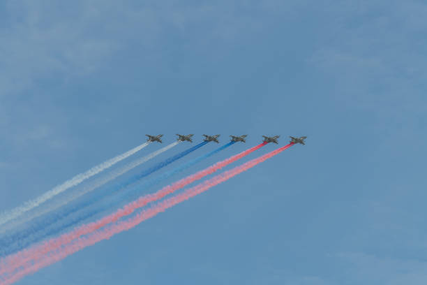 Russia, Moscow - May 07, 2022: Group of military aircrafts flies in formation with three colored smoke in shape of russian flag in the sky during Victory Day parade in Russia.