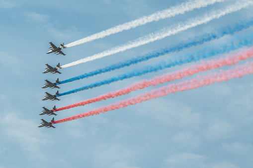 Russia, Moscow - May 07, 2022: Group of military aircrafts flies in formation with three colored smoke in shape of russian flag in the sky during Victory Day parade in Russia.